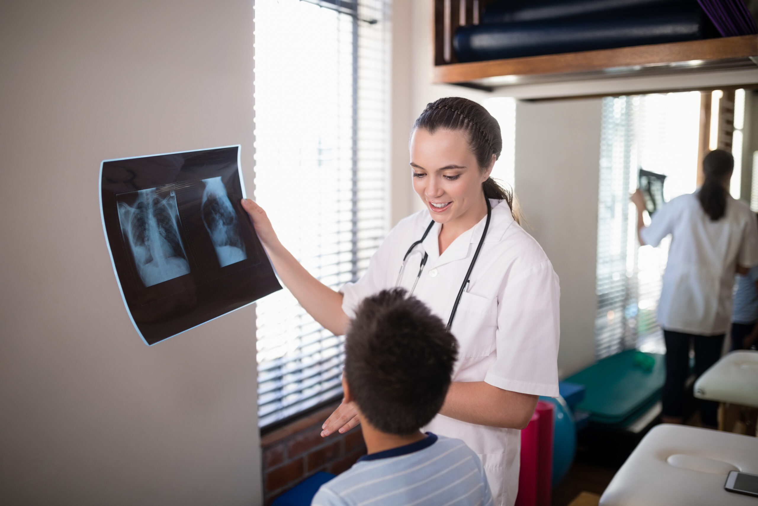 Female therapist holding x-ray while looking at boy