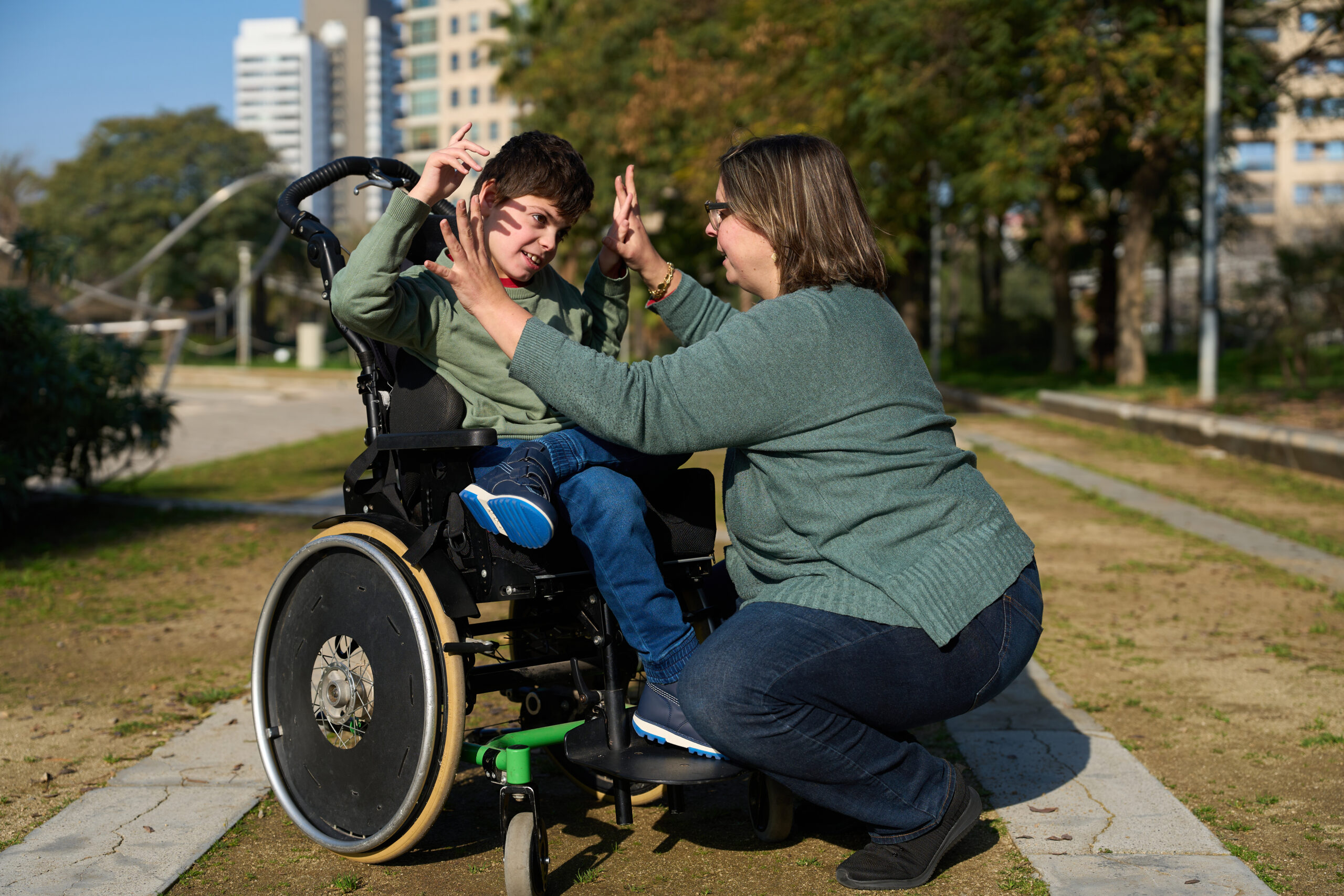 Mother and son with disability playing together in wheelchair in park
