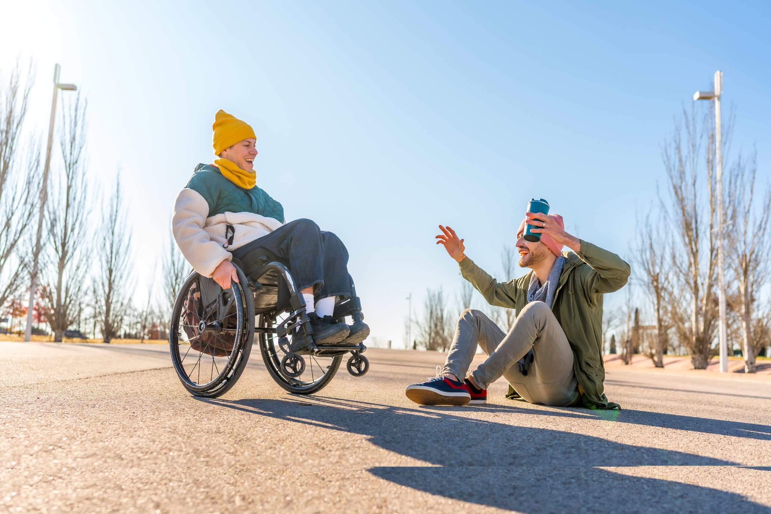 Young man playing with friend in wheelchair in a park