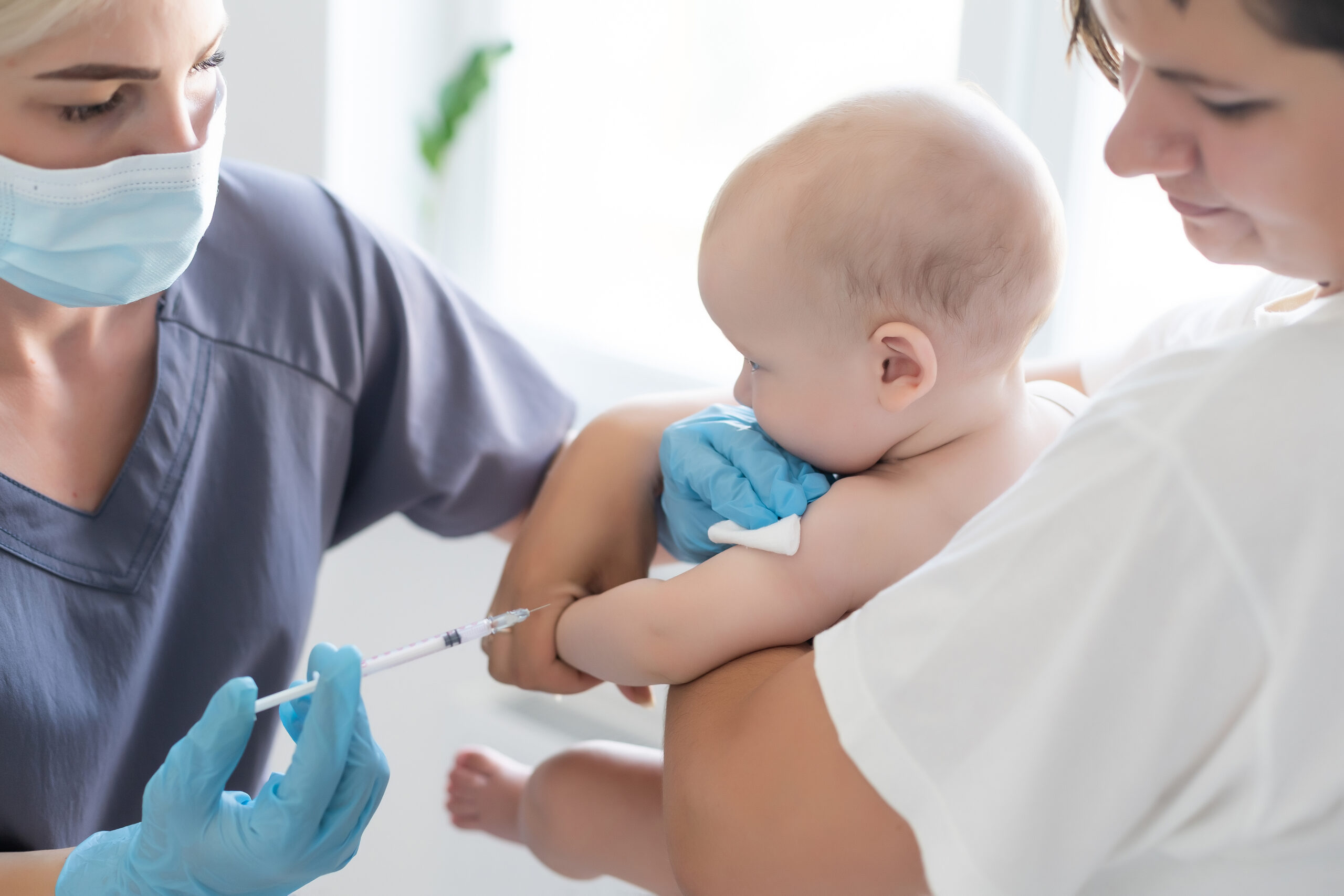 The doctor makes a baby vaccination on a white background.