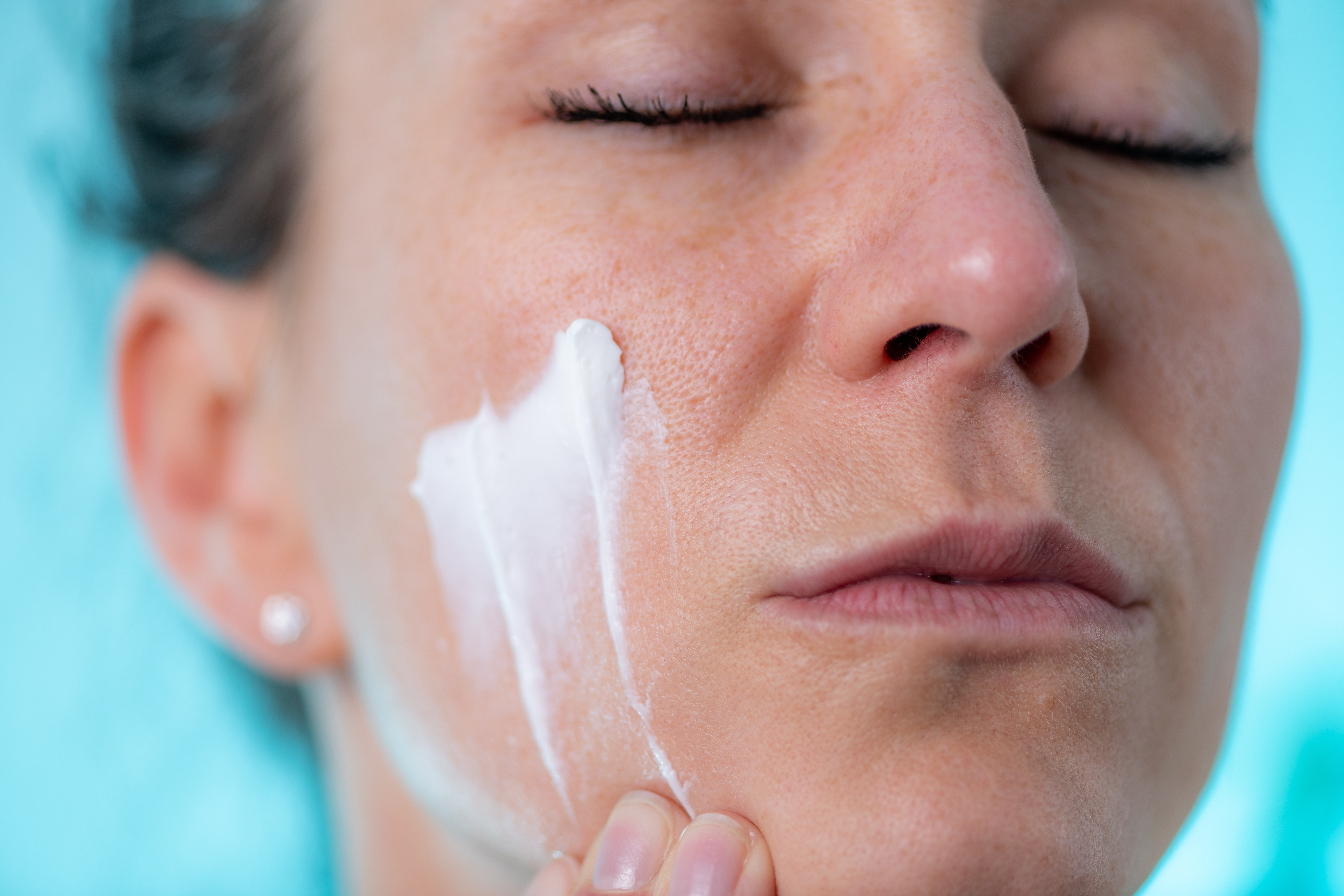 Woman applies cream to her face at home