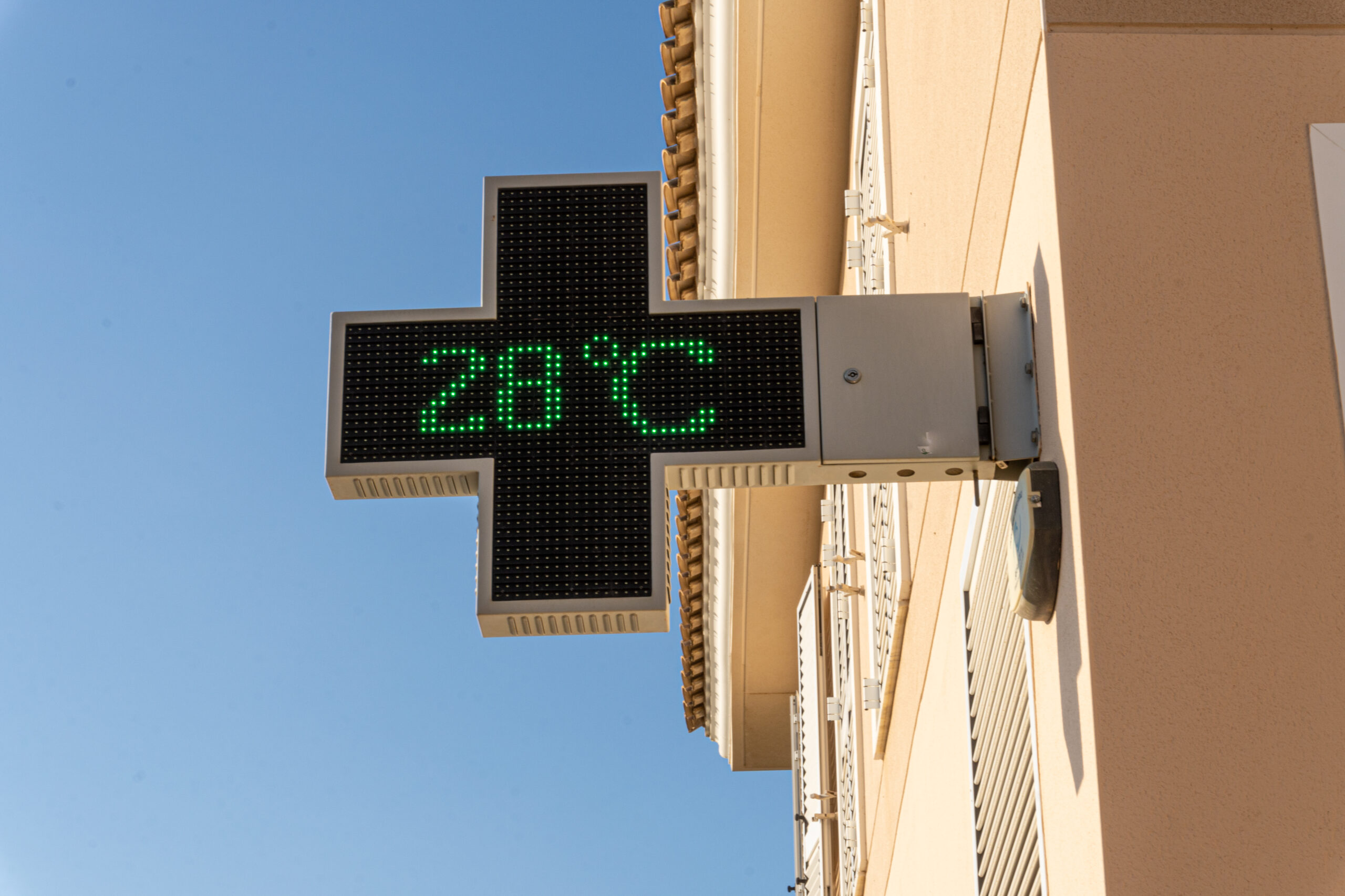 Closeup shot of a pharmacy sign with a 28 Celsius temperature outside