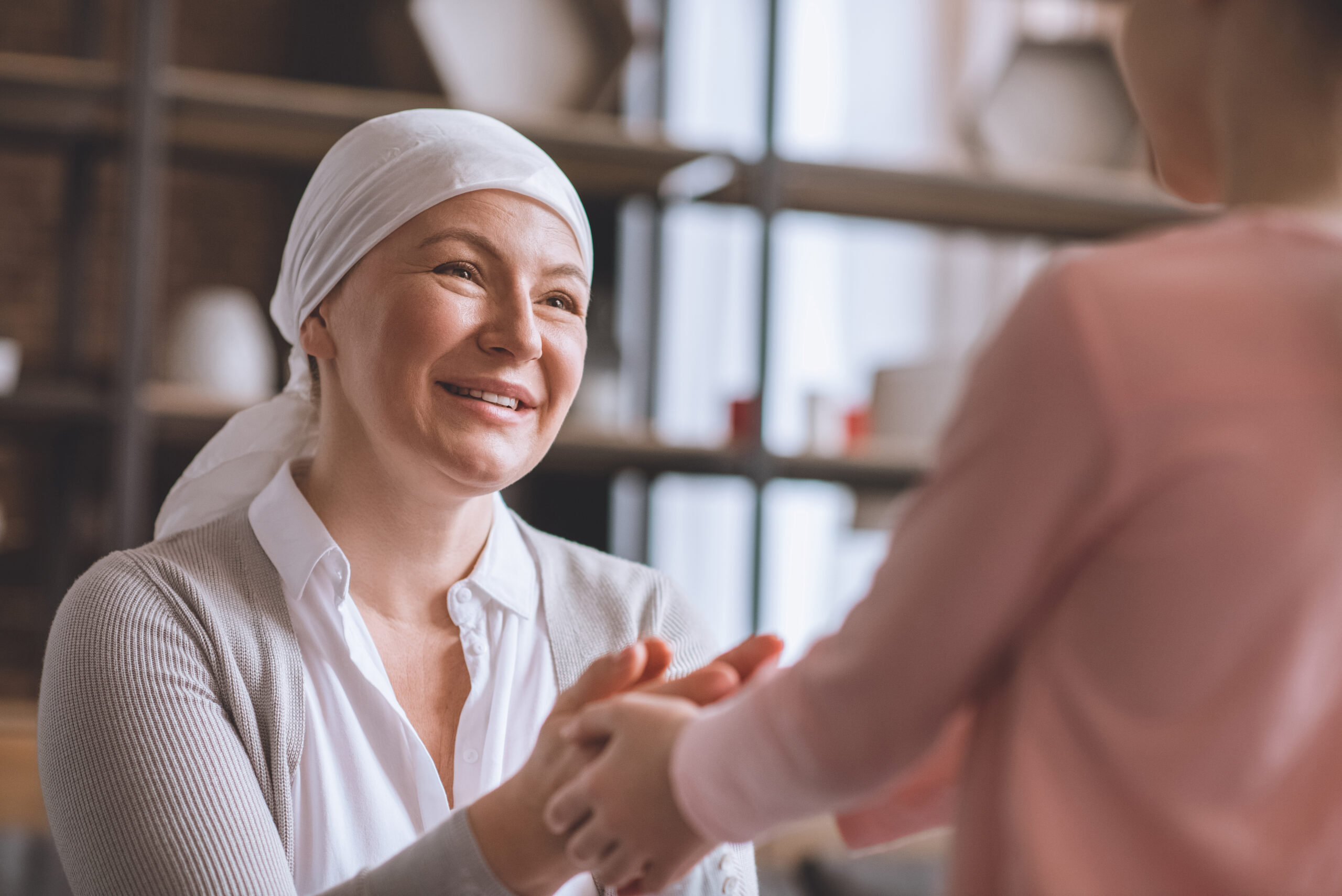 cropped shot of kid and sick smiling mature woman in kerchief holding hands