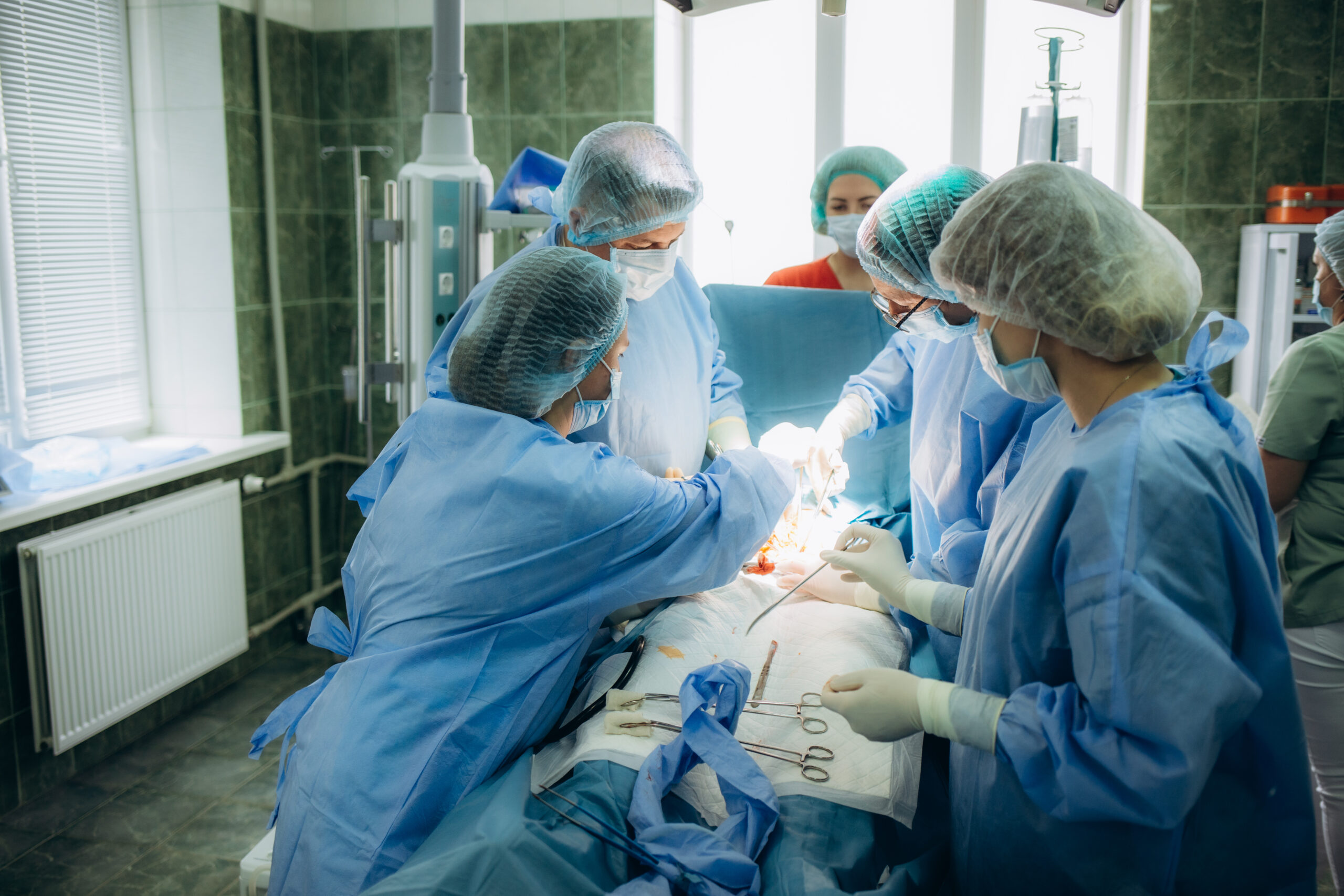 surgeons perfoming surgery operation of abdominal cesarean section during child delivery birth at clinic operating room
