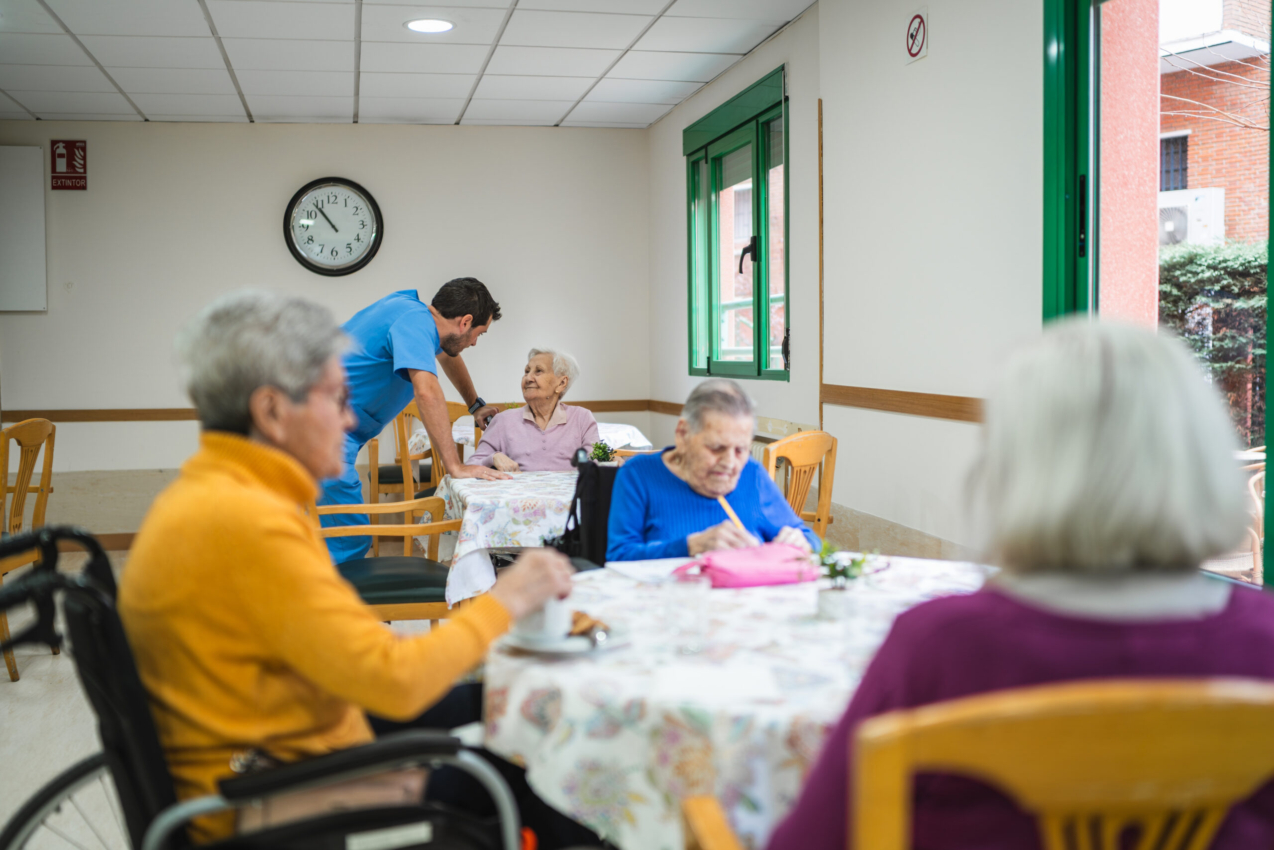 Caregiver assisting elderly woman in nursing home