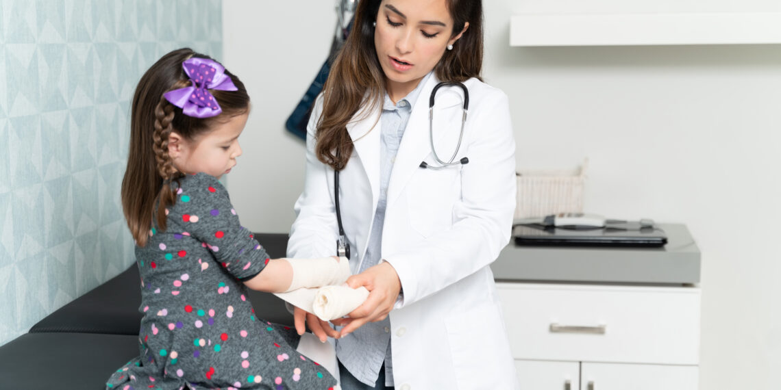 Doctor Putting Bandage On Injured Hand Of Girl