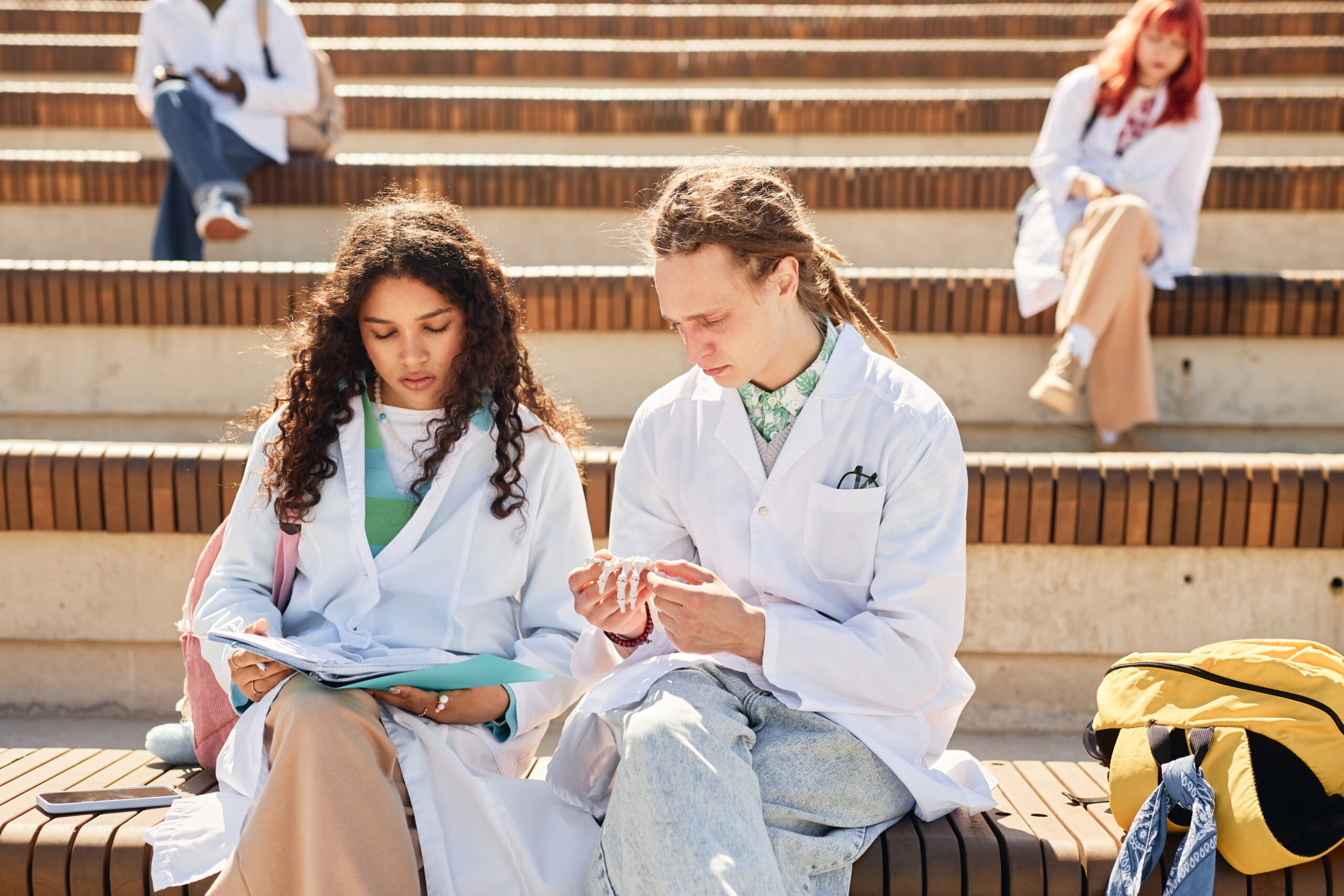 Male and Female Med Students Examining Skeleton Models Studying Outdoors