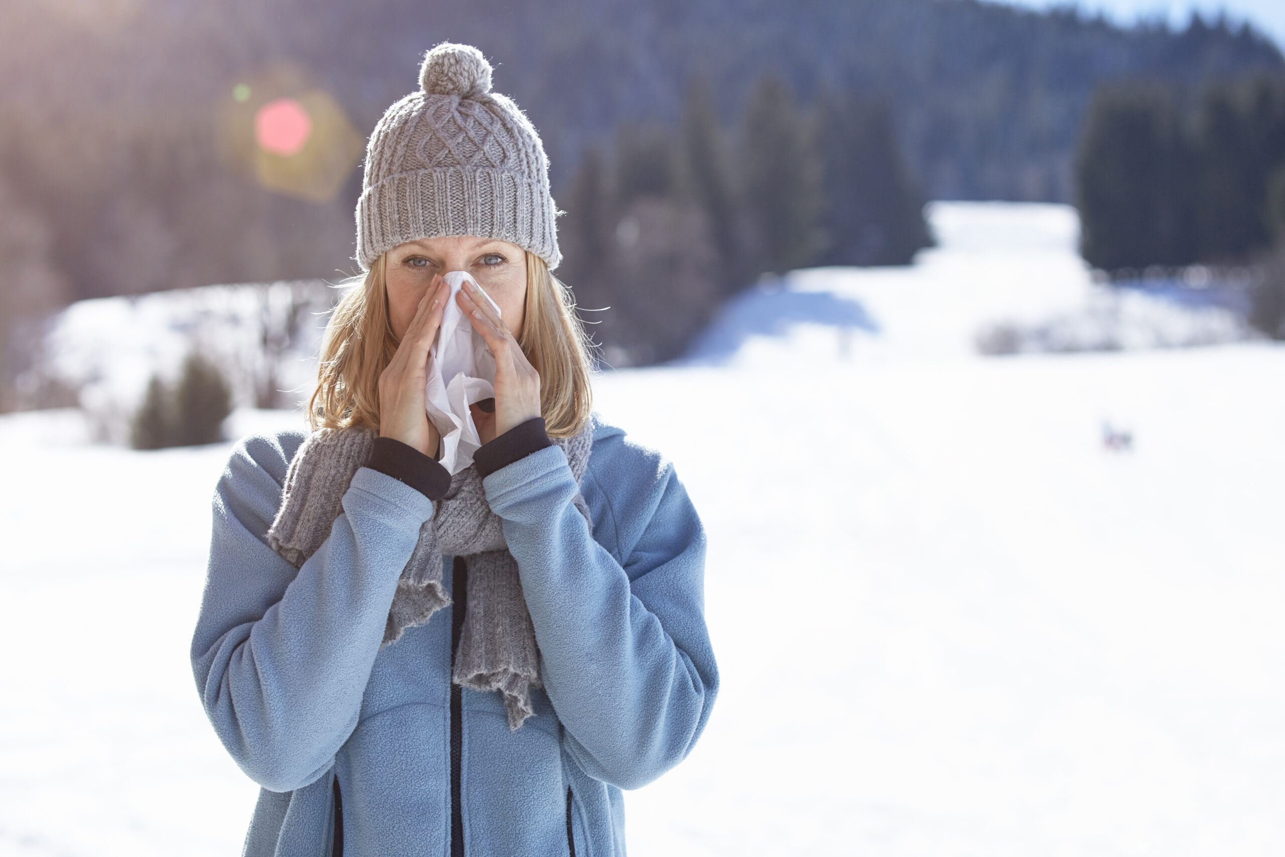 Woman blowing her nose on a cold winter's day outdoors