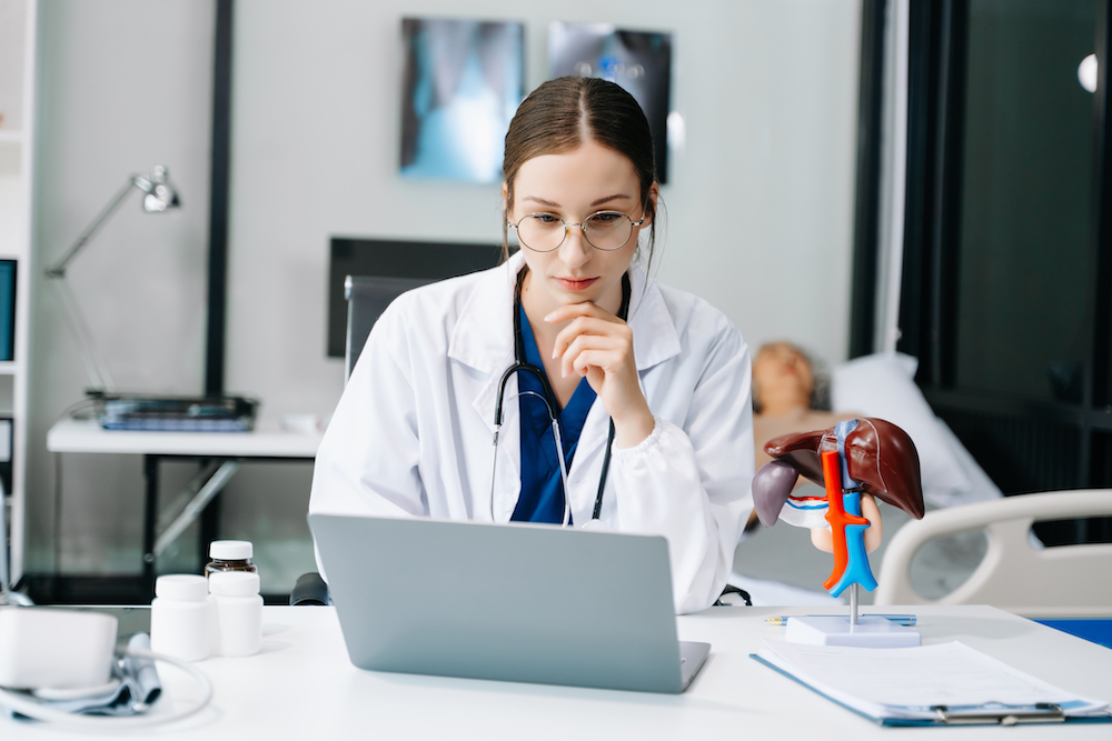 Young female doctor in white medical uniform using laptop and tablet talking video conference call at desk,Doctor sitting at desk and writing a prescription for her patient