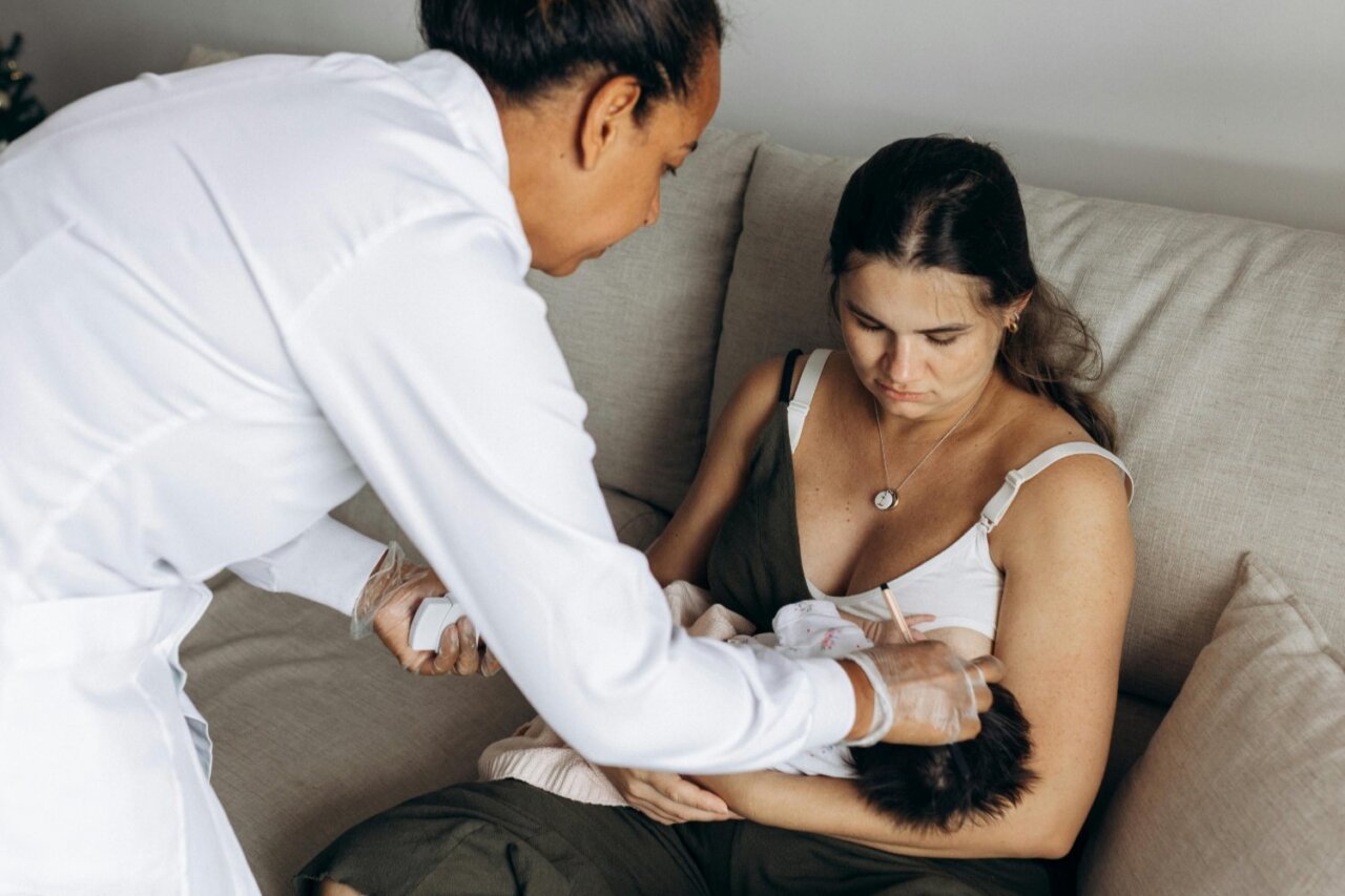 Mujer en consulta de salud materna con un bebé en brazos.