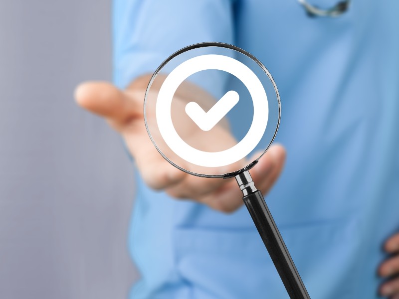 Médico sosteniendo una lupa con un símbolo de verificación