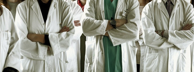 Médicos en concentración con batas blancas, brazos cruzados