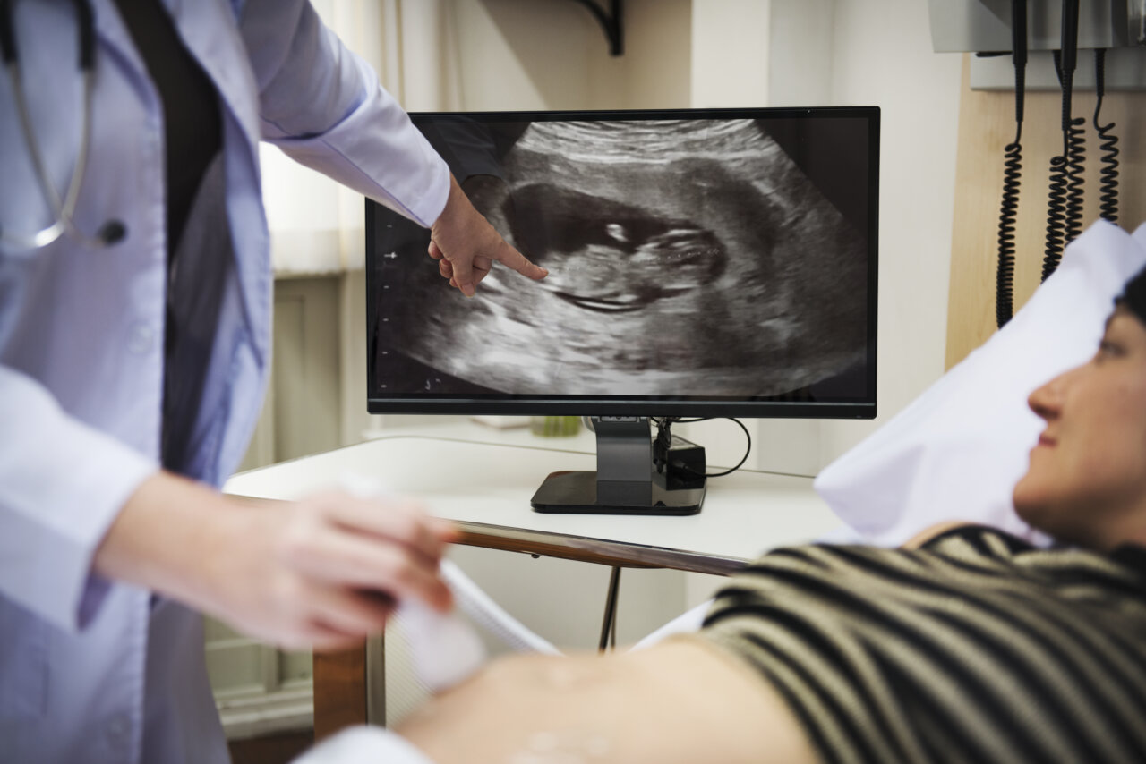Un médico explica los resultados de un ultrasonido a una paciente embarazada.
