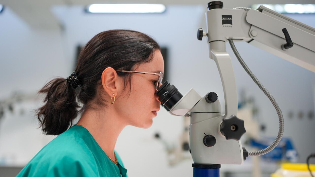 Mujer observando a través de un microscopio en un entorno médico