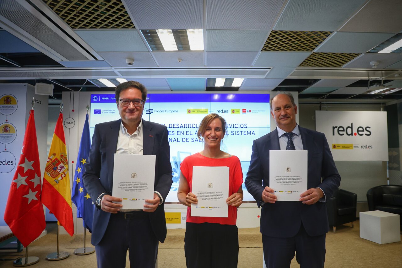 Fondos para IA en Sanidad Pública Tres personas sosteniendo documentos en un evento sobre IA en sanidad