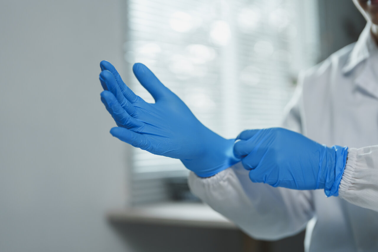 Médico con guantes estériles Médico colocando guantes estériles azules en un entorno hospitalario