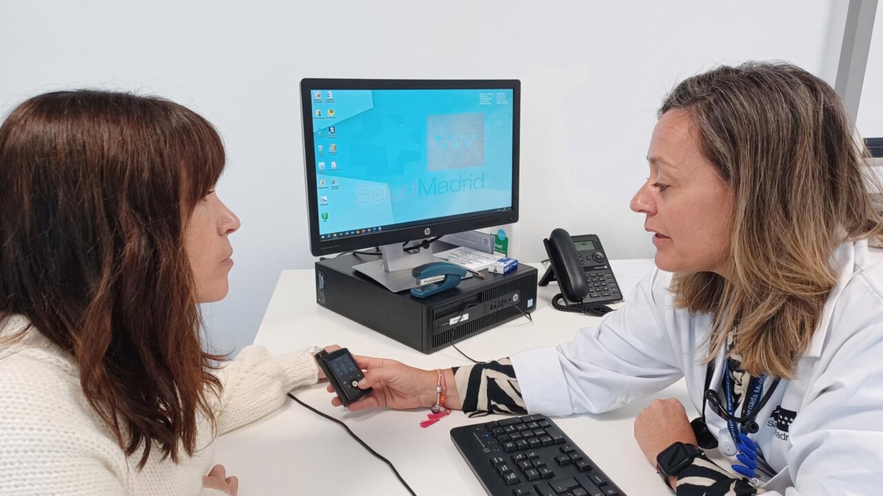 Médico revisando un dispositivo de salud con paciente en consulta